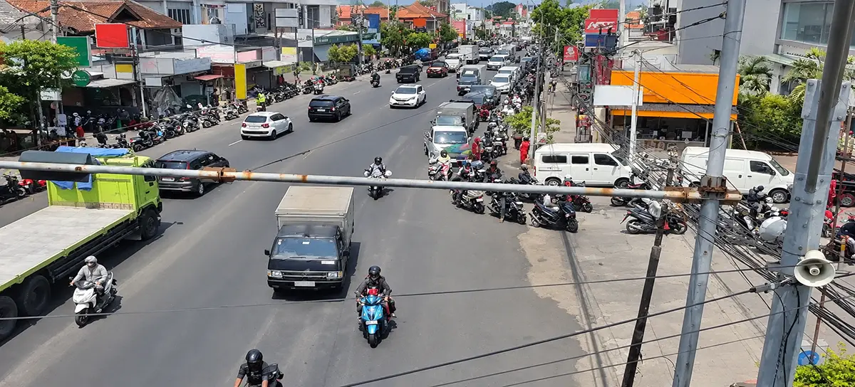 Deretan sepeda motor mengantre di sisi kanan jalan raya yang ramai, difoto dari atas